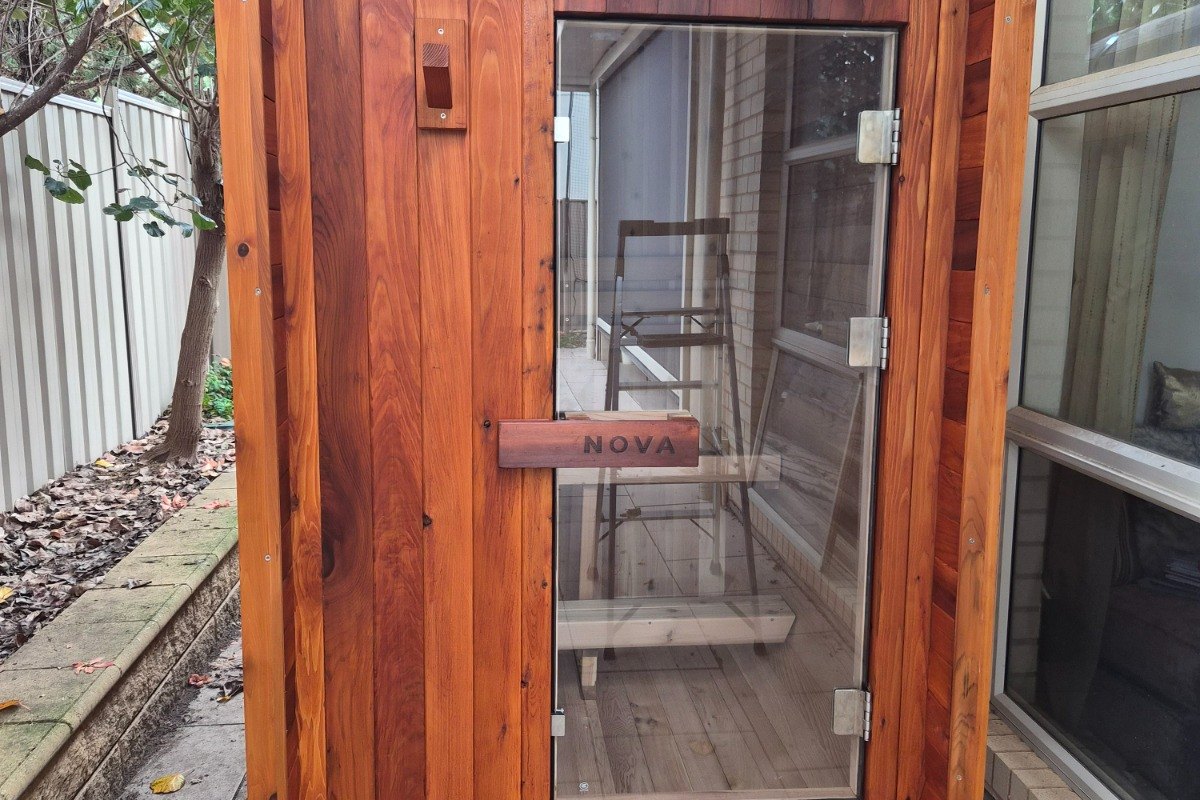 Nova Sauna Lite outdoor sauna with rich timber colour beside a home