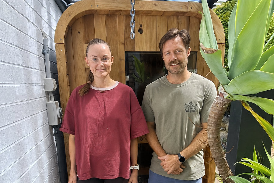 Couple standing in front of their Nova Sauna Lite 2 person outdoor sauna